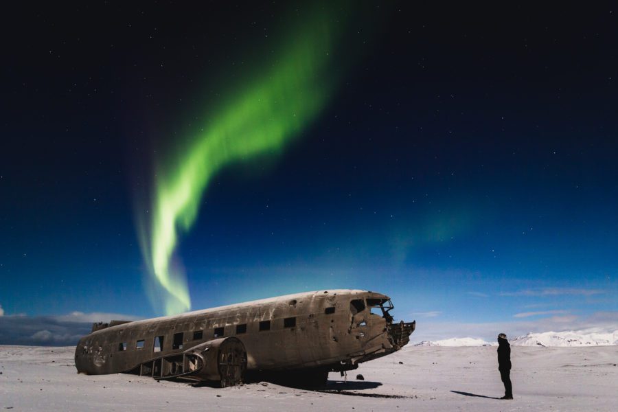 Green northern lights arc above the Sólheimasandur DC-3 plane wreck on Iceland's south coast.