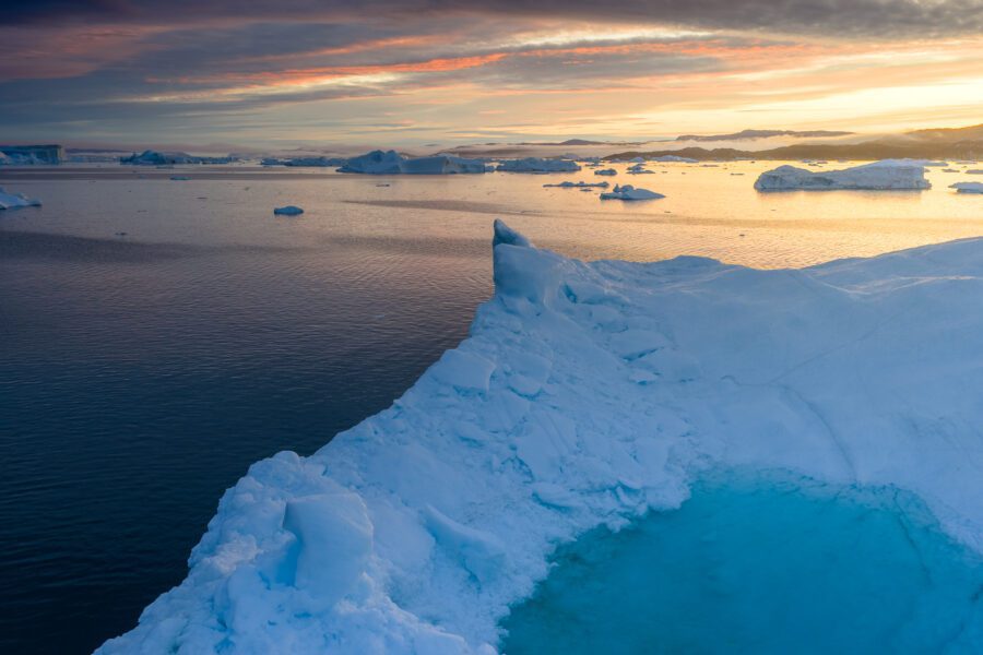 Iceberg edge at sunrise above the ice-filled waters of Disko Bay, Greenland.