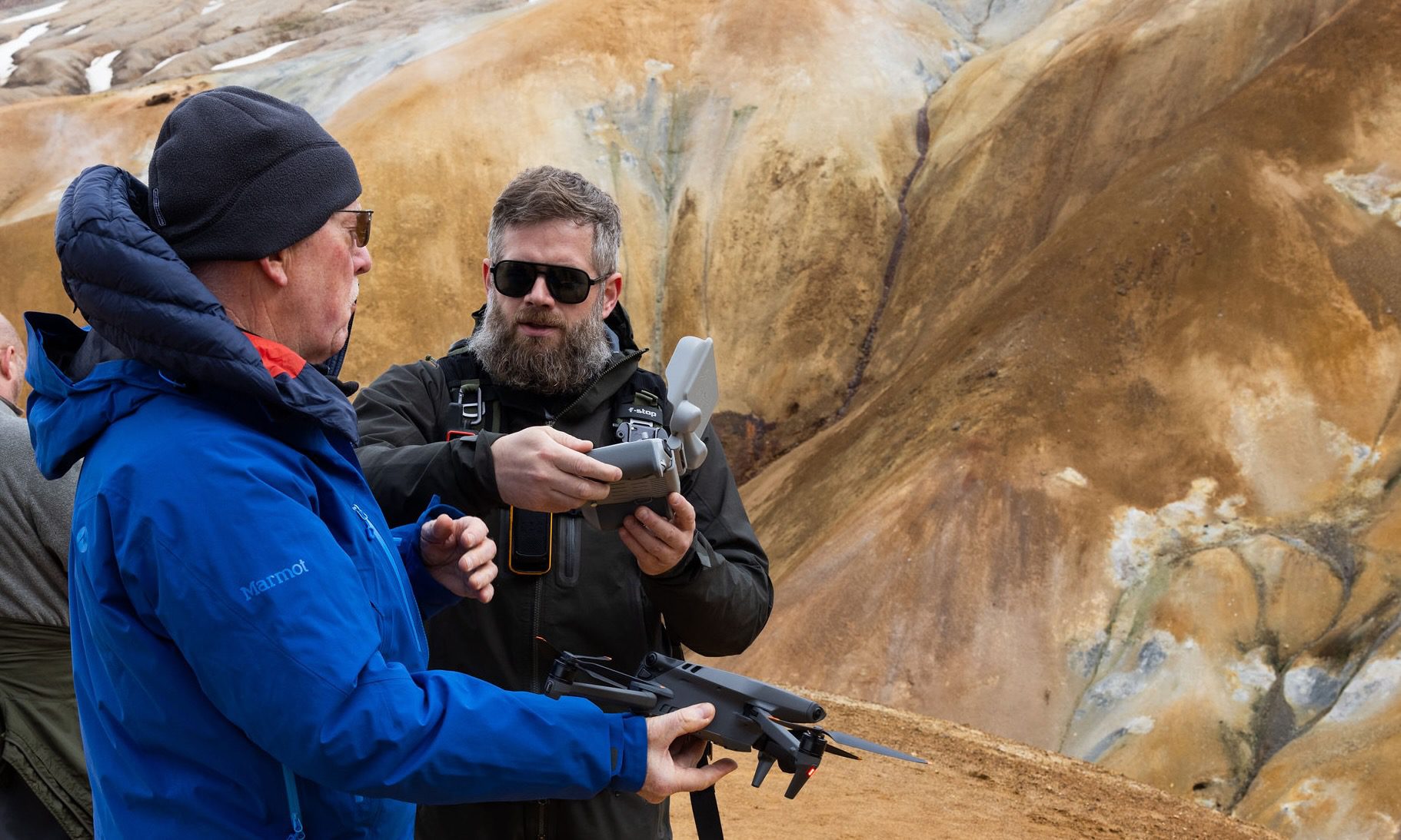Workshop instructor showing a guest the drone controller in the colourful hills of Hveradalir, Iceland.