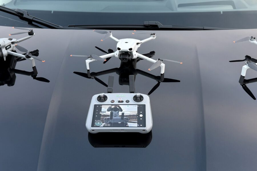 DJI Lito 1, Lito X1 and Mini 5 Pro drones with their controllers laid out on a car bonnet.